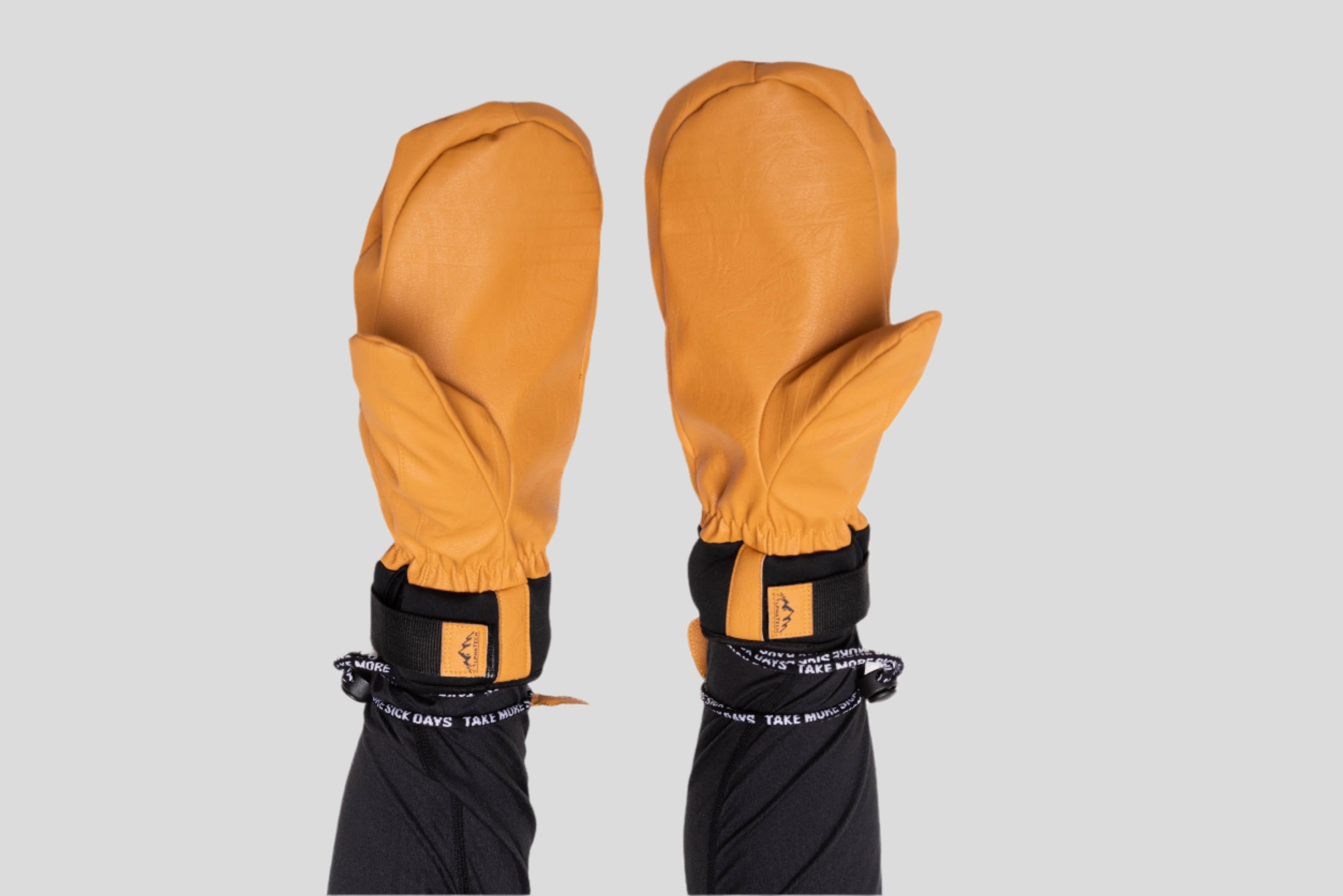 Pair of mustard yellow climbing gloves with black straps on a white background